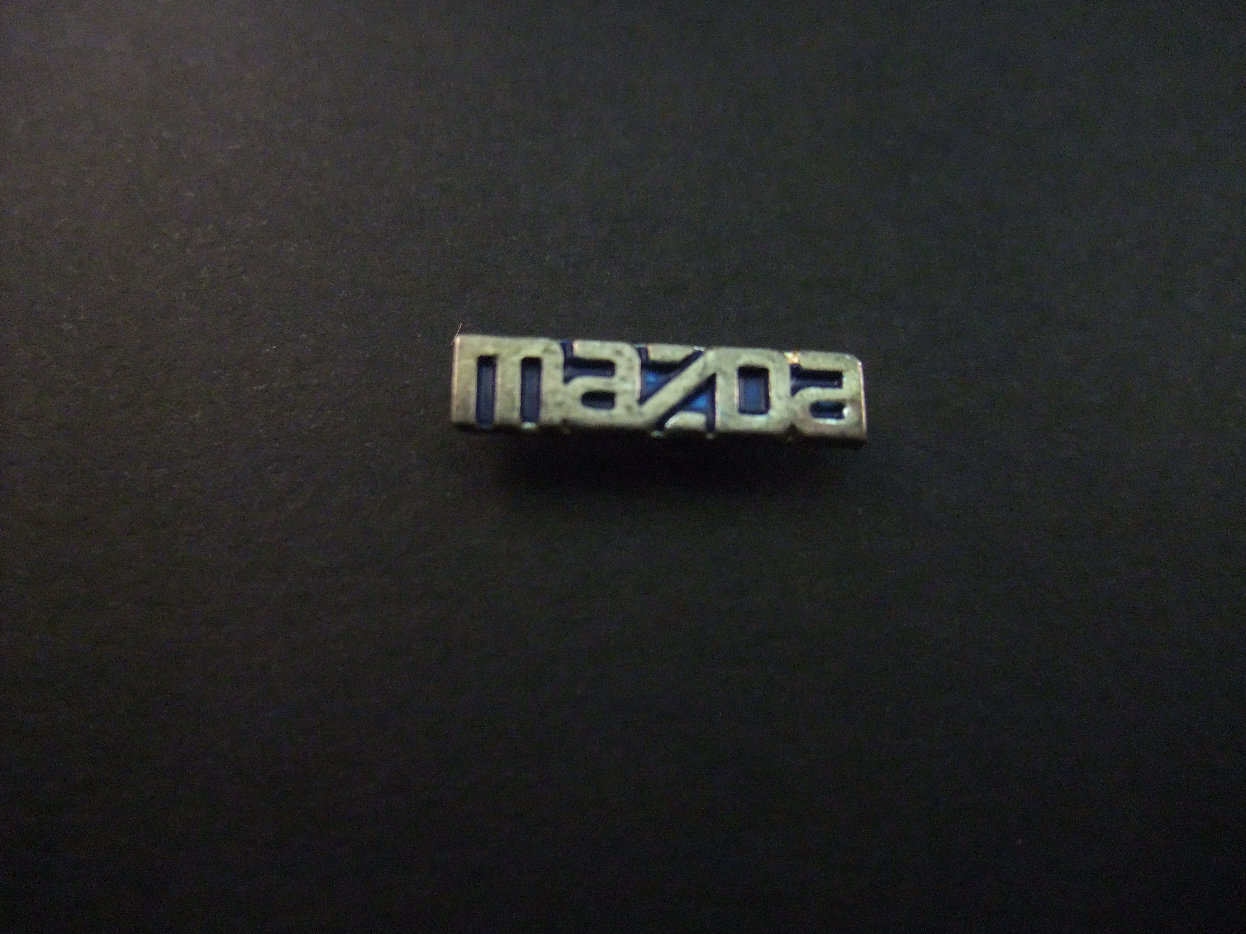 Mazda logo zilverkleurig, blauwe achtergrond